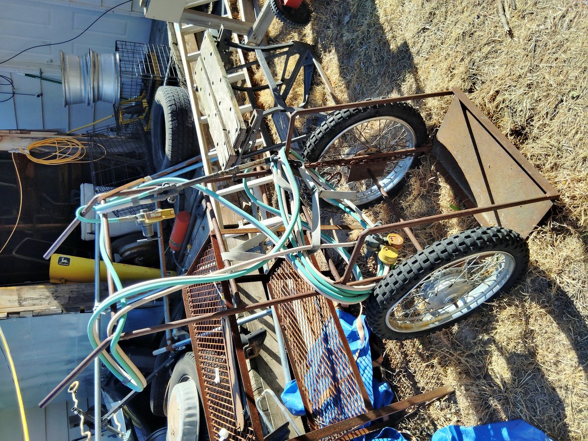 Rusty metal cart with wheels and hoses outside