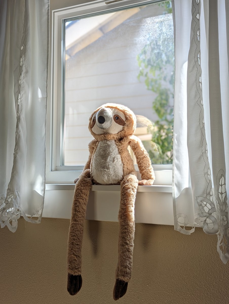 Stuffed sloth toy sitting on windowsill